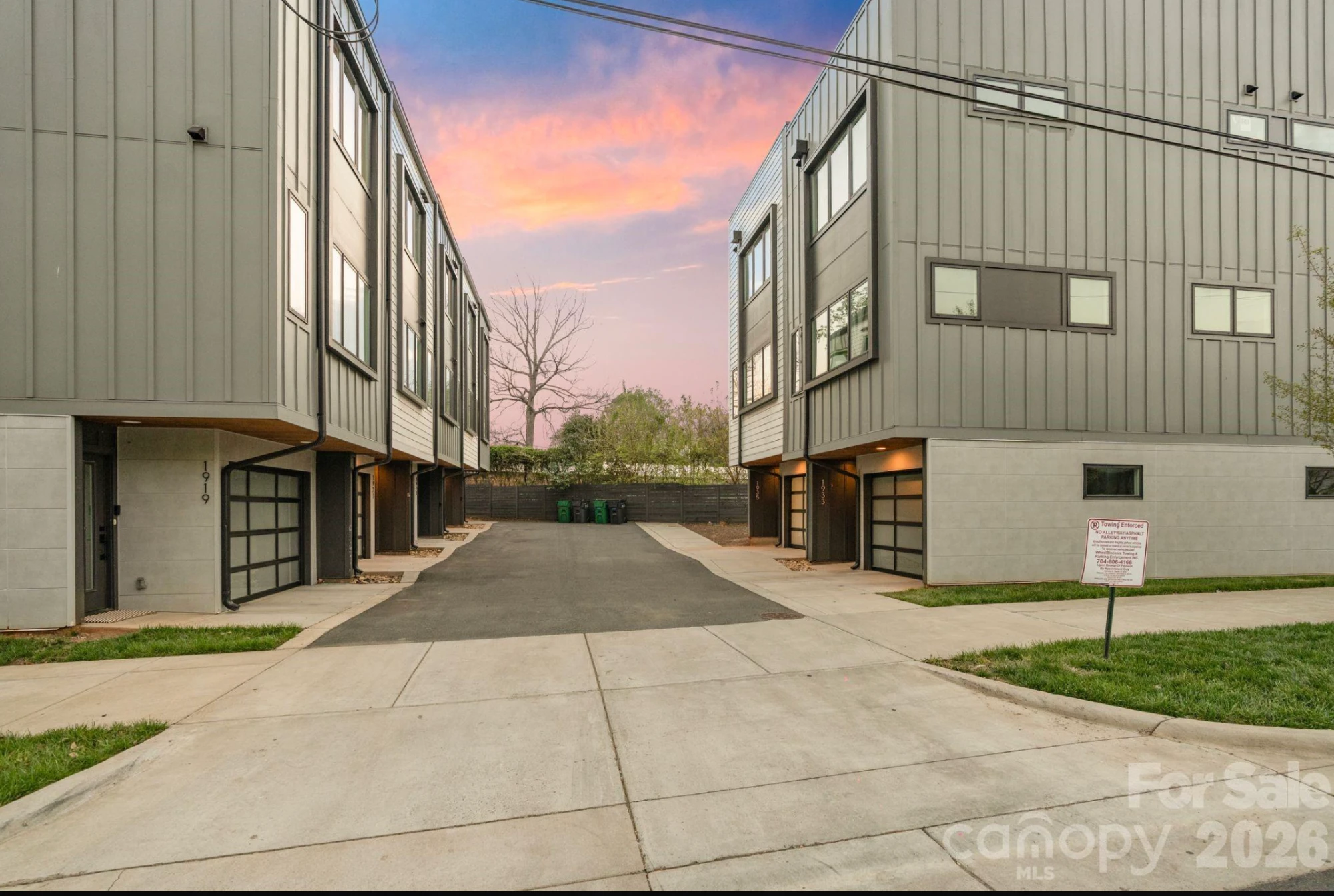 Exterior of the modern townhome community at dusk, showing private drive and attached two-car garages