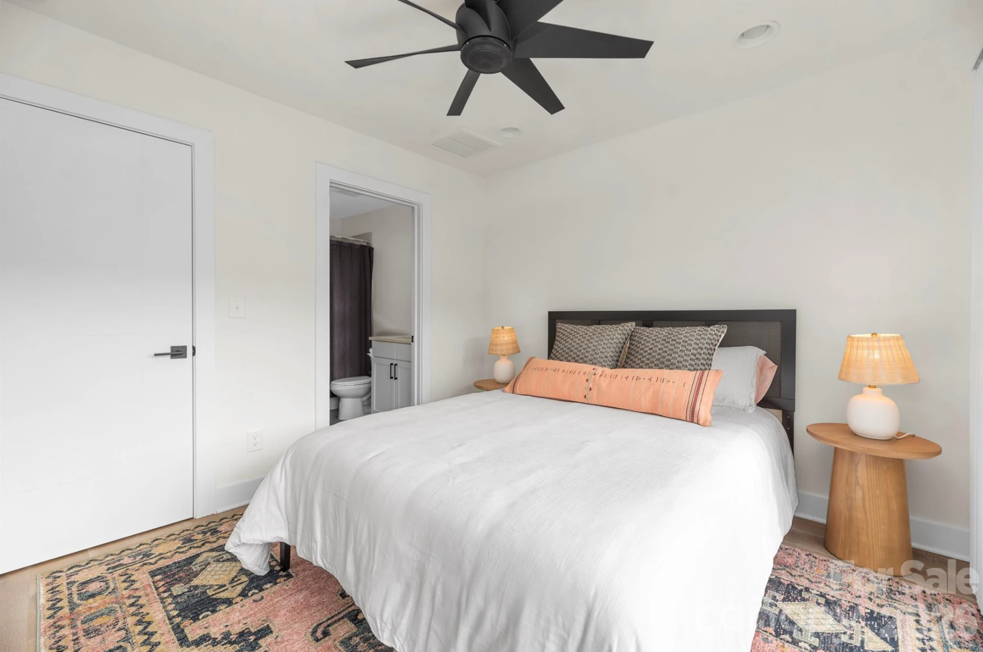 Guest bedroom with queen bed, ceiling fan, layered rug, and a private en-suite bath